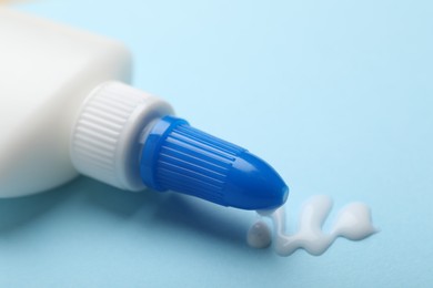 Photo of Bottle of glue on light blue background, closeup