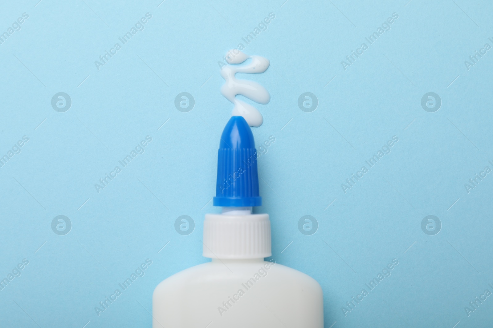 Photo of Bottle of glue on light blue background, top view