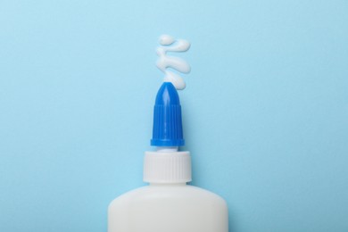 Photo of Bottle of glue on light blue background, top view