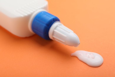 Photo of Bottle of glue on orange background, closeup