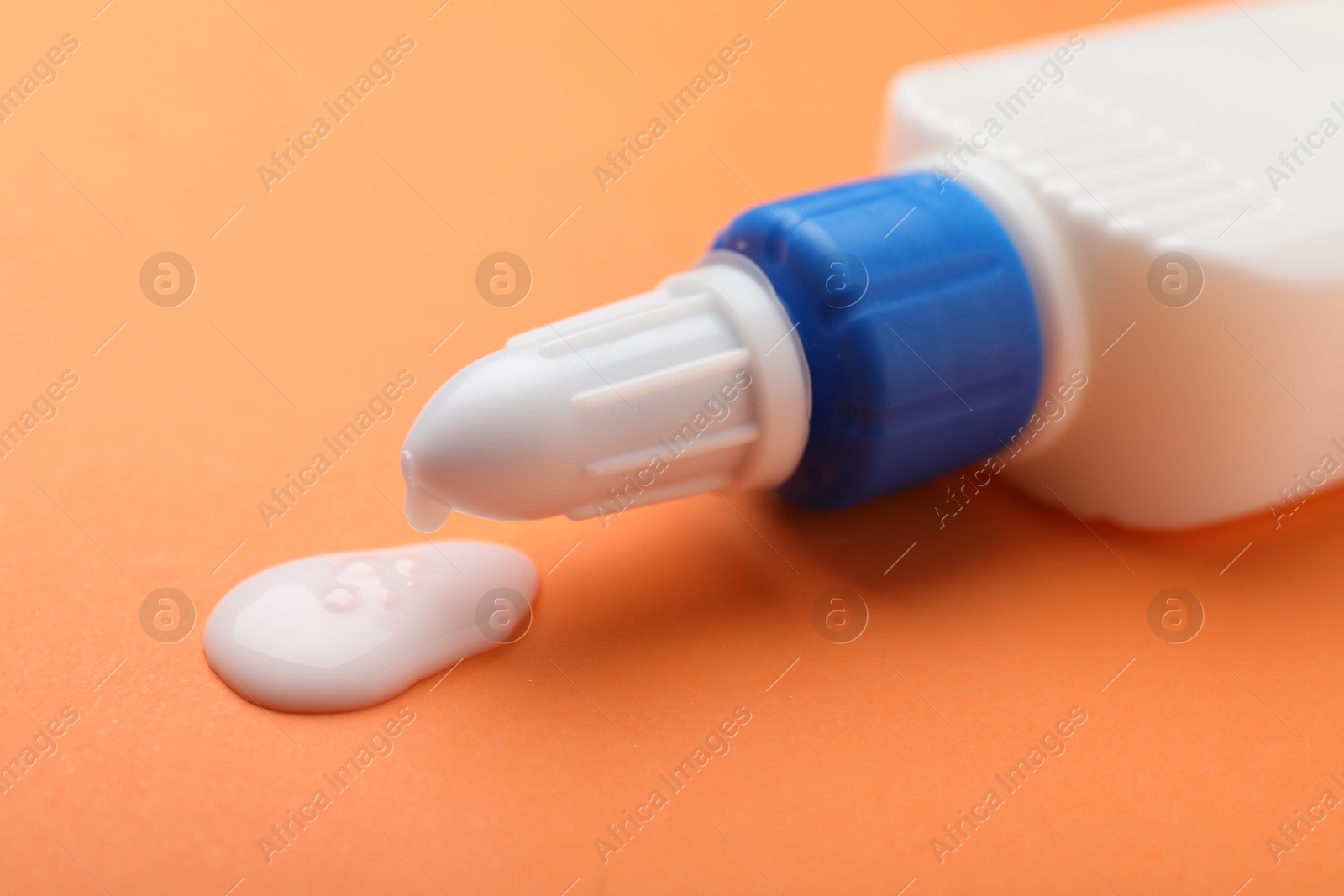 Photo of Bottle of glue on orange background, closeup