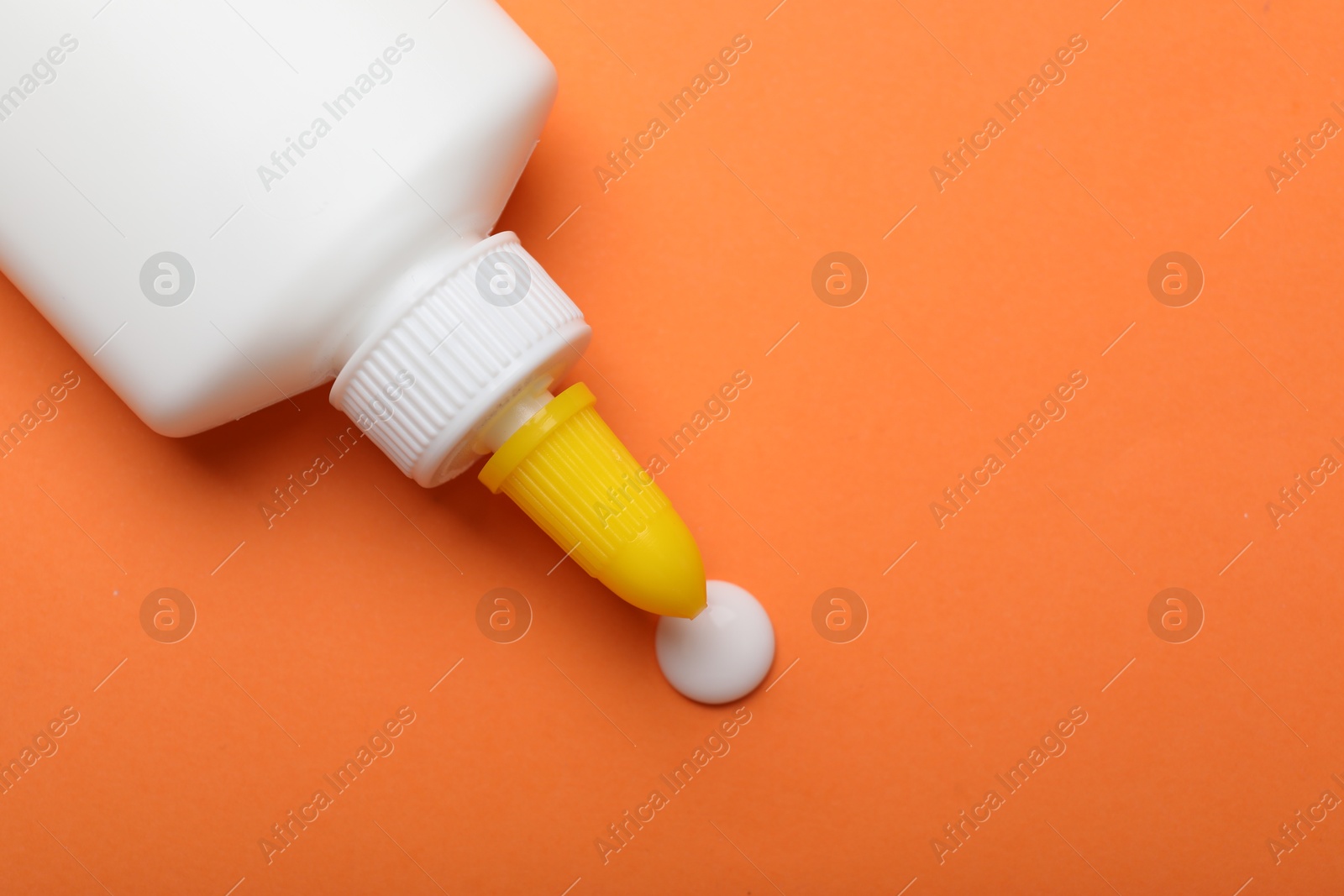 Photo of Bottle of glue on orange background, top view. Space for text