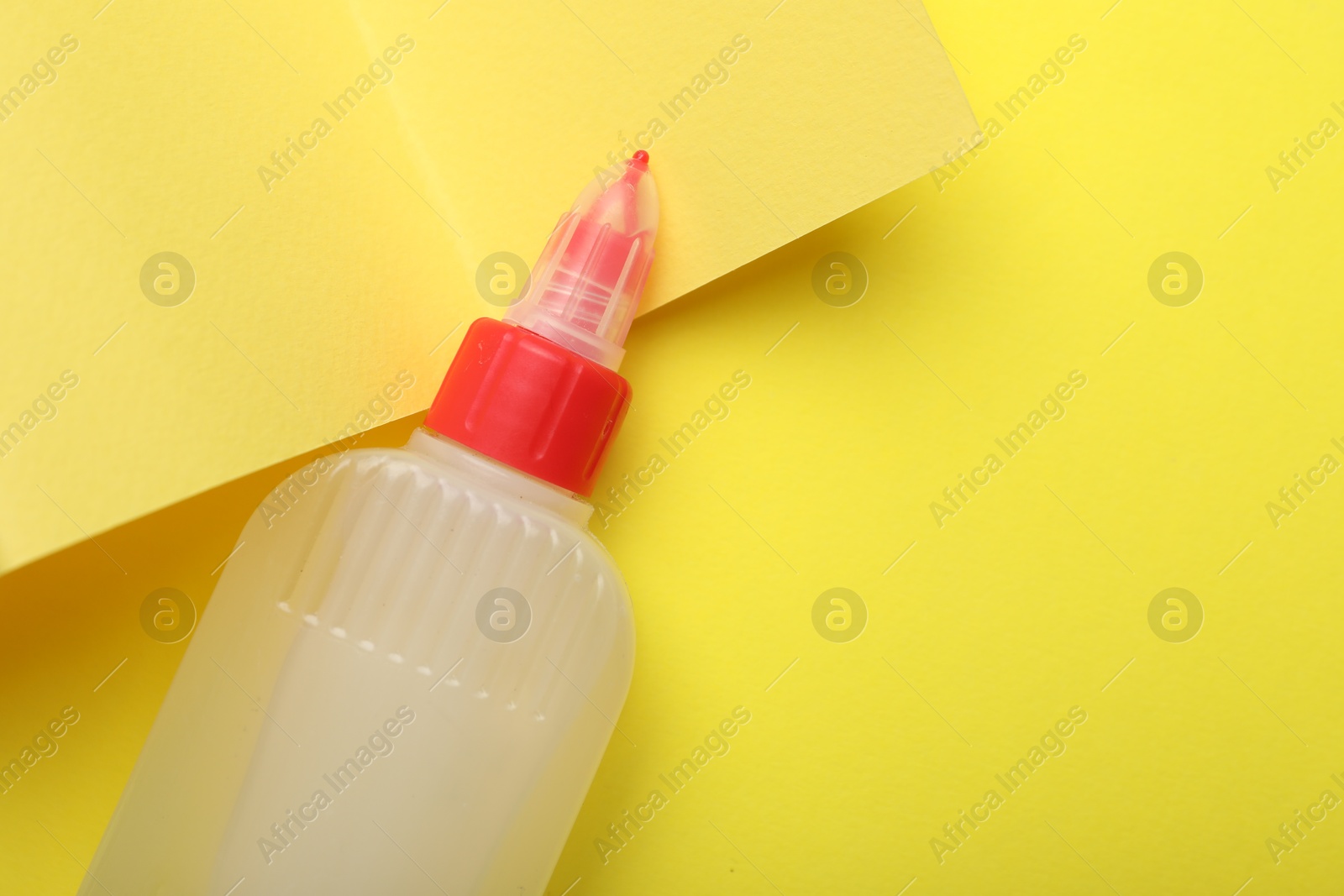 Photo of Bottle of glue on yellow background, top view. Space for text