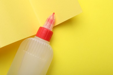 Photo of Bottle of glue on yellow background, top view. Space for text