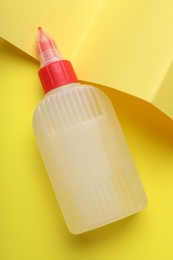 Photo of Bottle of glue on yellow background, top view