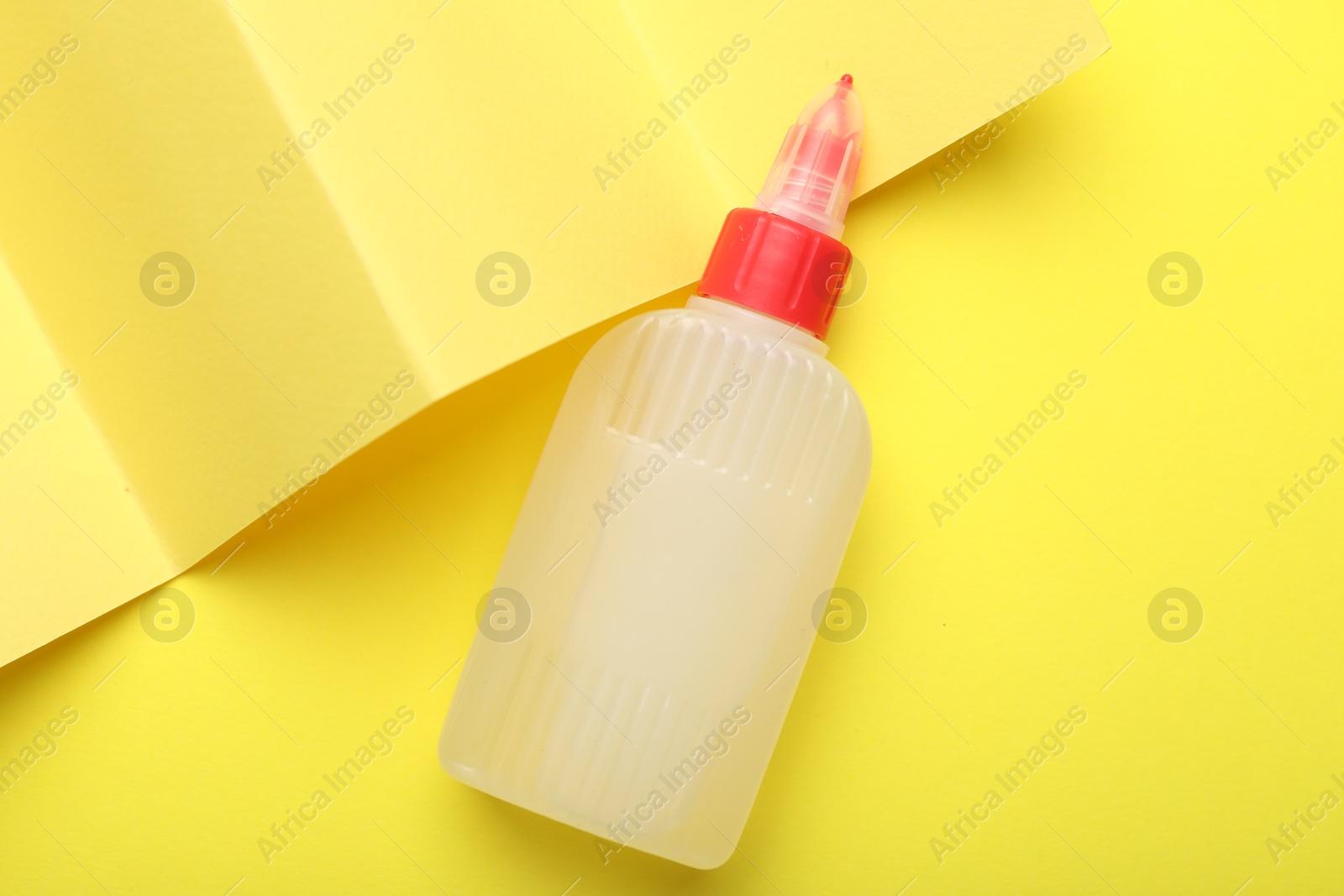 Photo of Bottle of glue on yellow background, top view