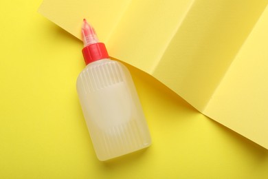 Photo of Bottle of glue on yellow background, top view