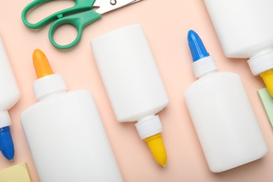 Photo of Bottles of glue, scissors and notes on beige background, flat lay