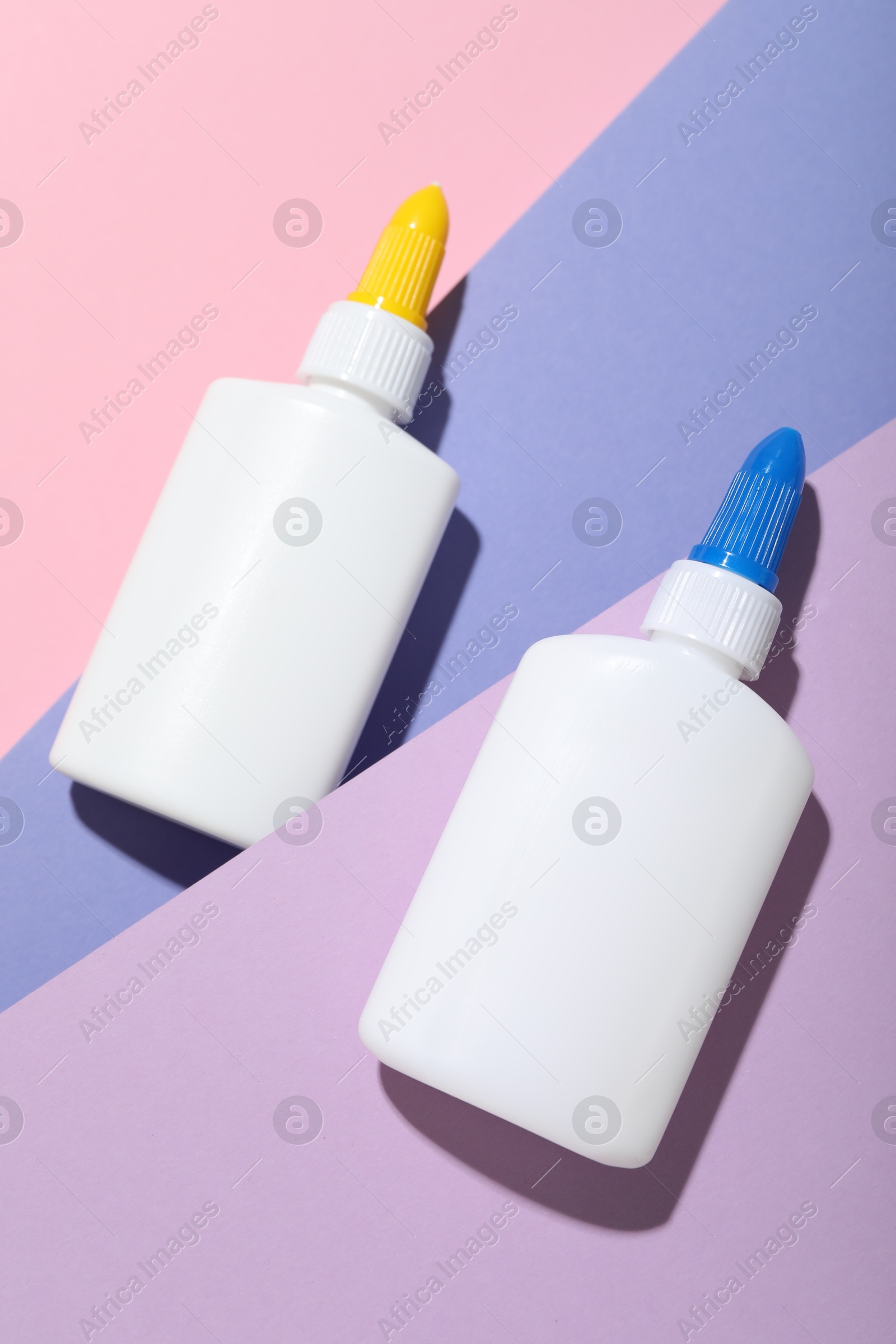 Photo of Bottles of glue on color background, flat lay