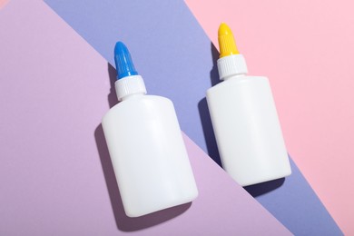 Photo of Bottles of glue on color background, flat lay