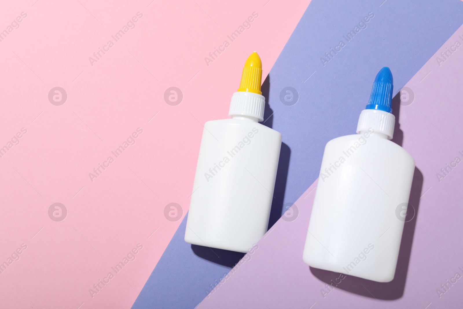 Photo of Bottles of glue on color background, flat lay. Space for text