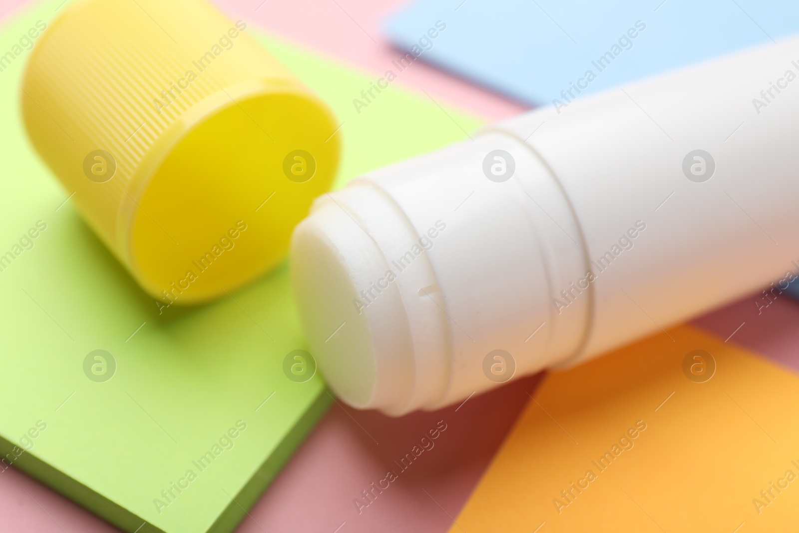 Photo of Stick of glue and notes on pink background, closeup