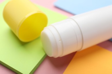 Photo of Stick of glue and notes on pink background, closeup