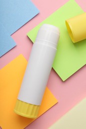 Photo of Stick of glue and notes on pink background, flat lay