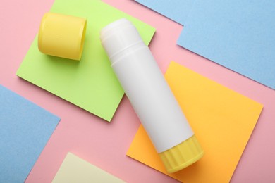 Photo of Stick of glue and notes on pink background, flat lay