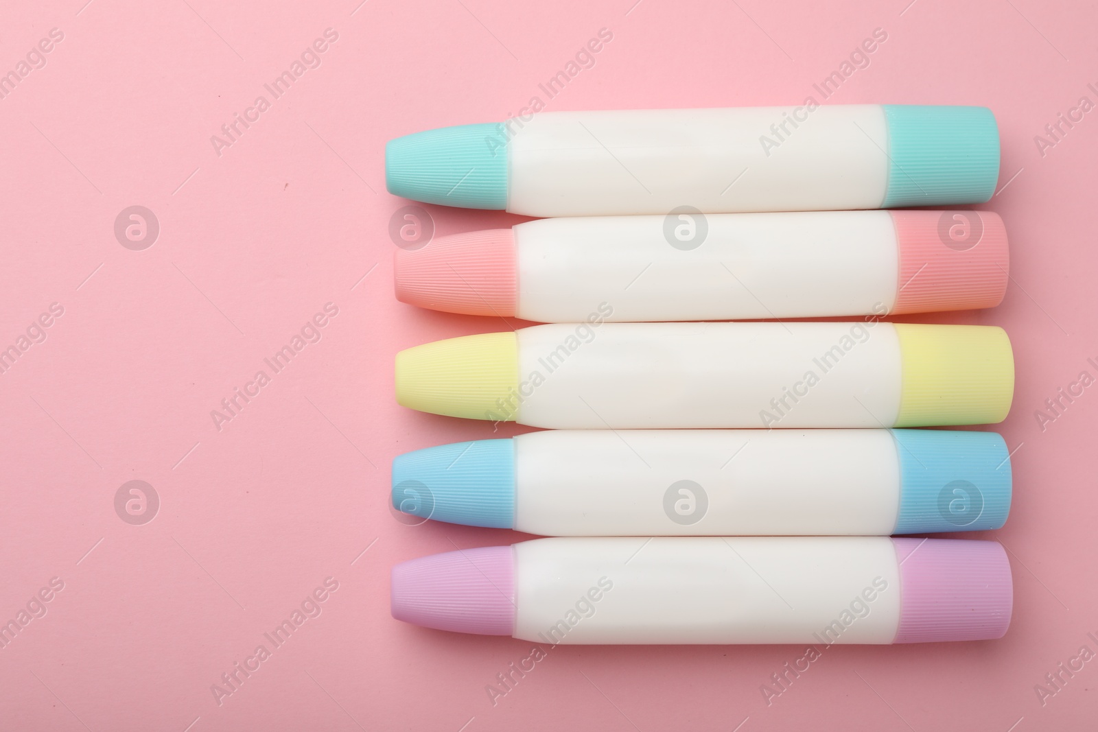 Photo of Sticks of glue on pink background, flat lay. Space for text