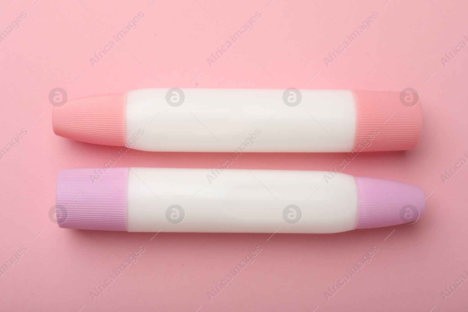 Photo of Sticks of glue on pink background, top view