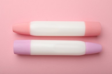 Photo of Sticks of glue on pink background, top view