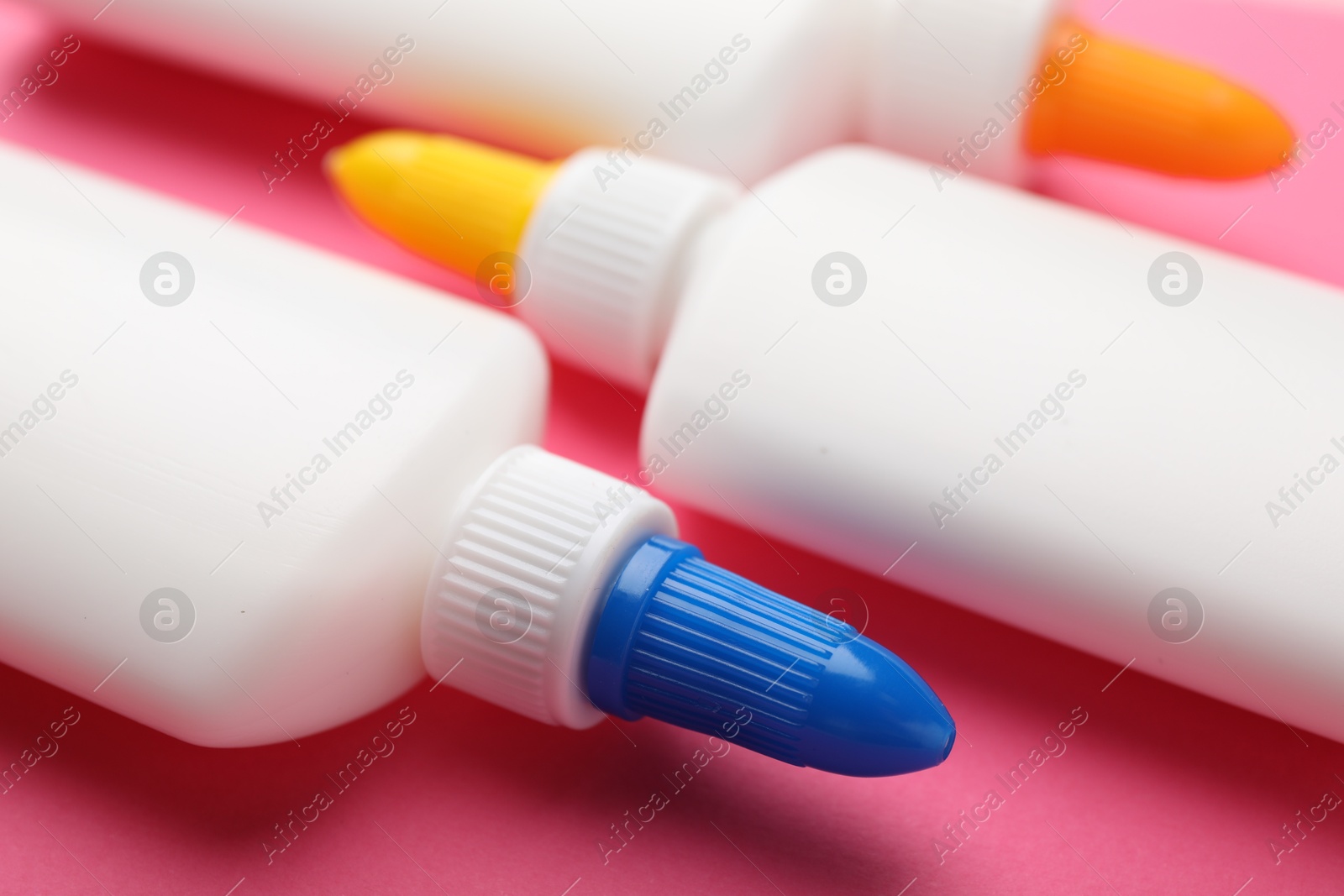 Photo of Bottles of glue on pink background, closeup