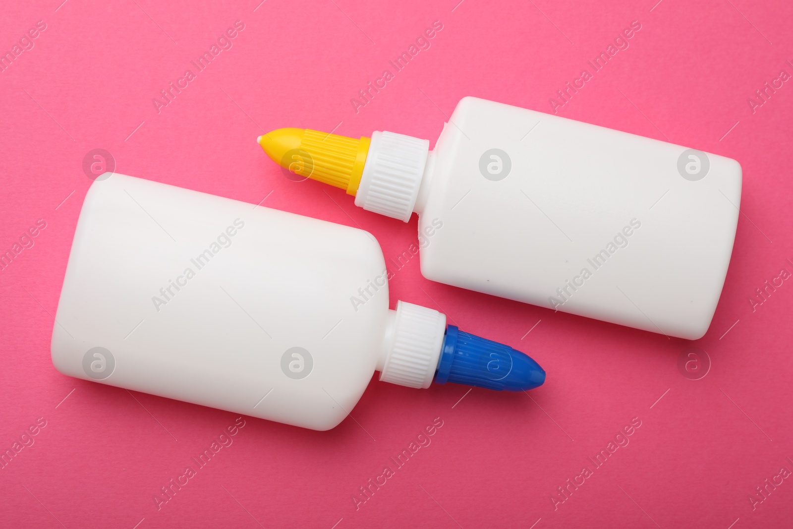 Photo of Bottles of glue on pink background, top view