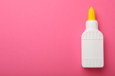 Photo of Bottle of glue on pink background, top view. Space for text