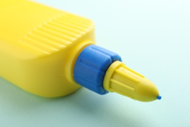 Photo of Bottle of glue on light blue background, closeup