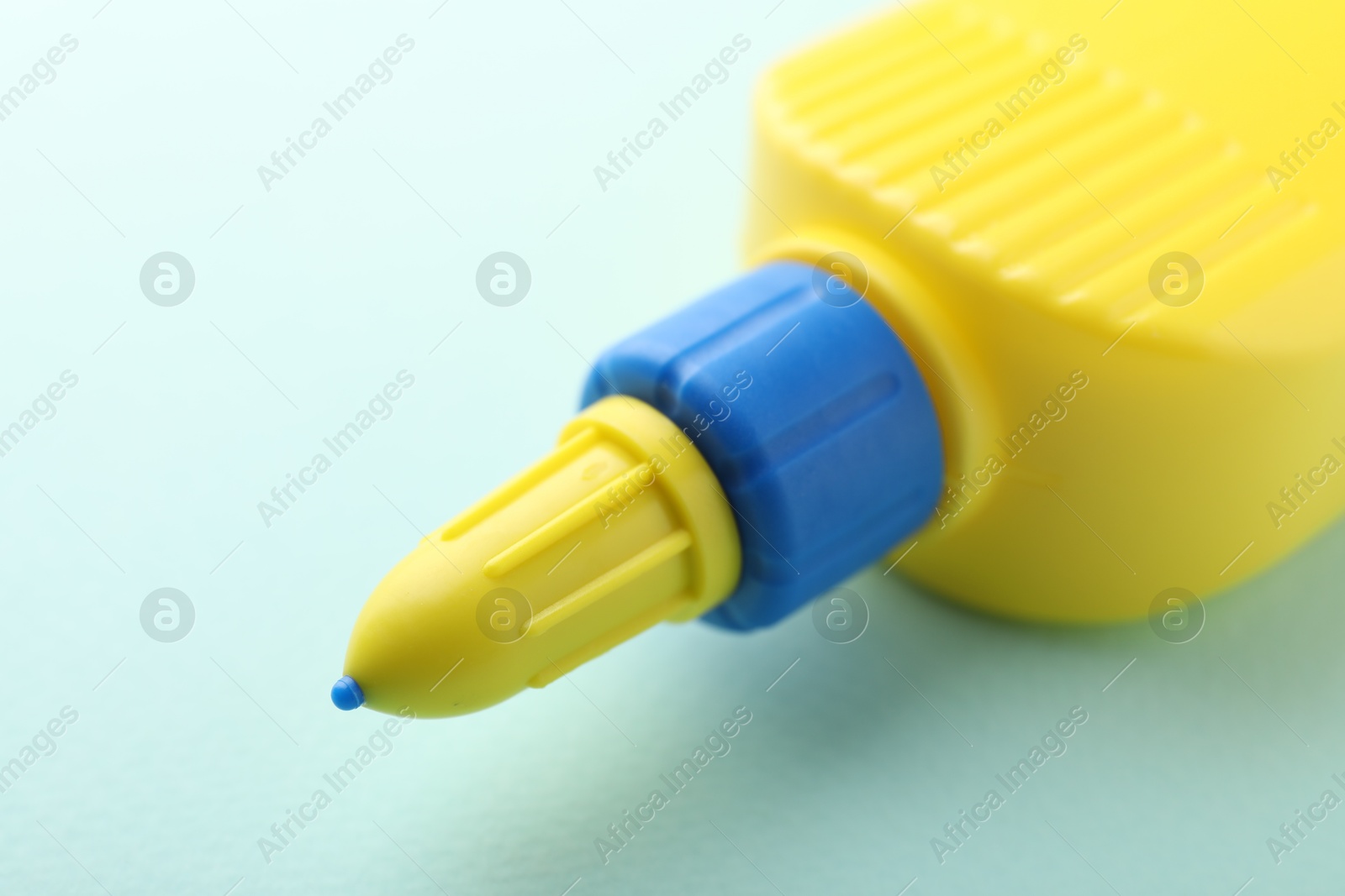 Photo of Bottle of glue on light blue background, closeup