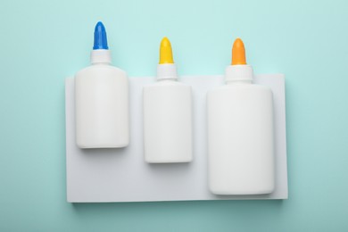 Photo of Bottles of glue on light blue background, top view