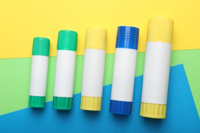 Photo of Sticks of glue on color background, flat lay