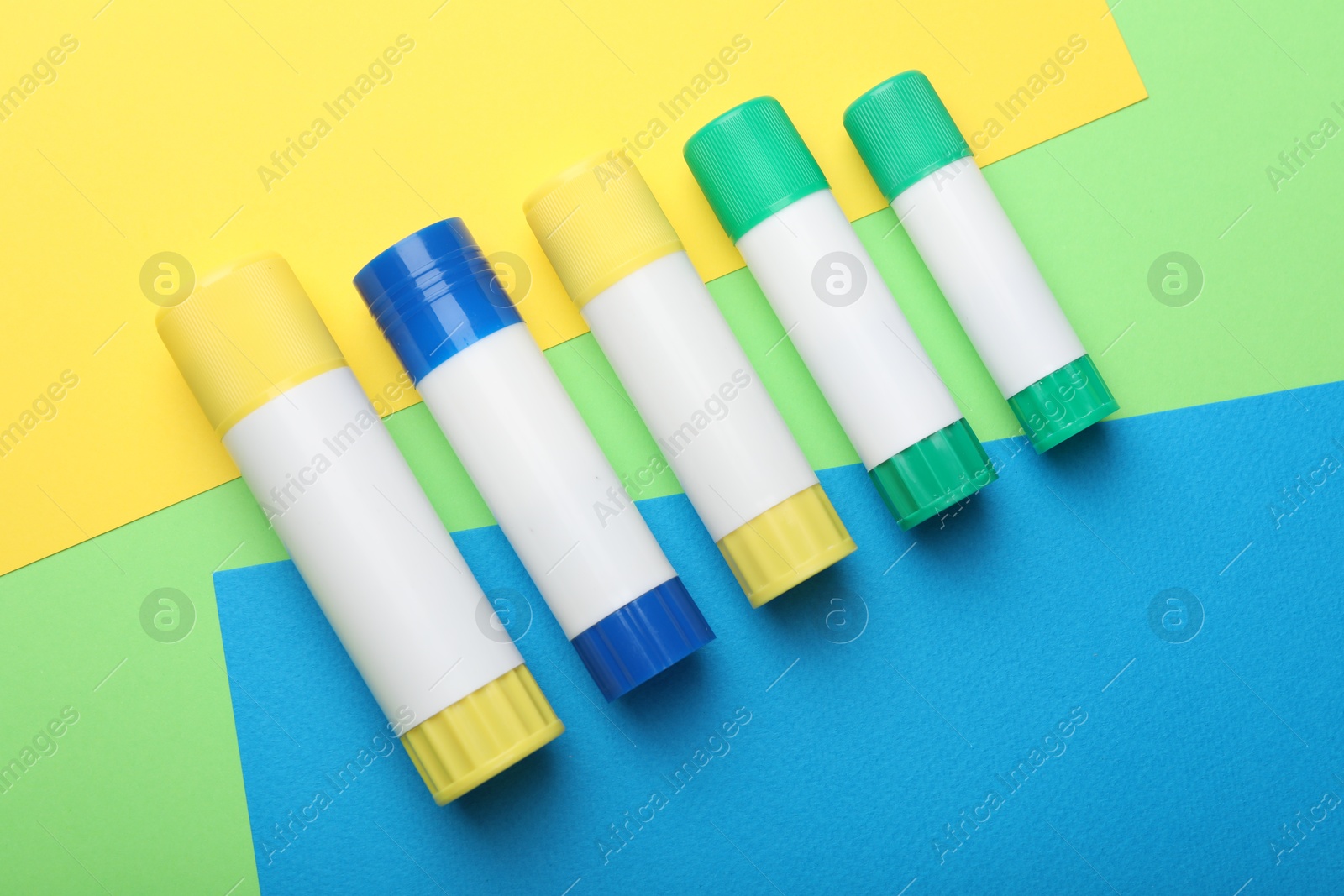 Photo of Sticks of glue on color background, flat lay