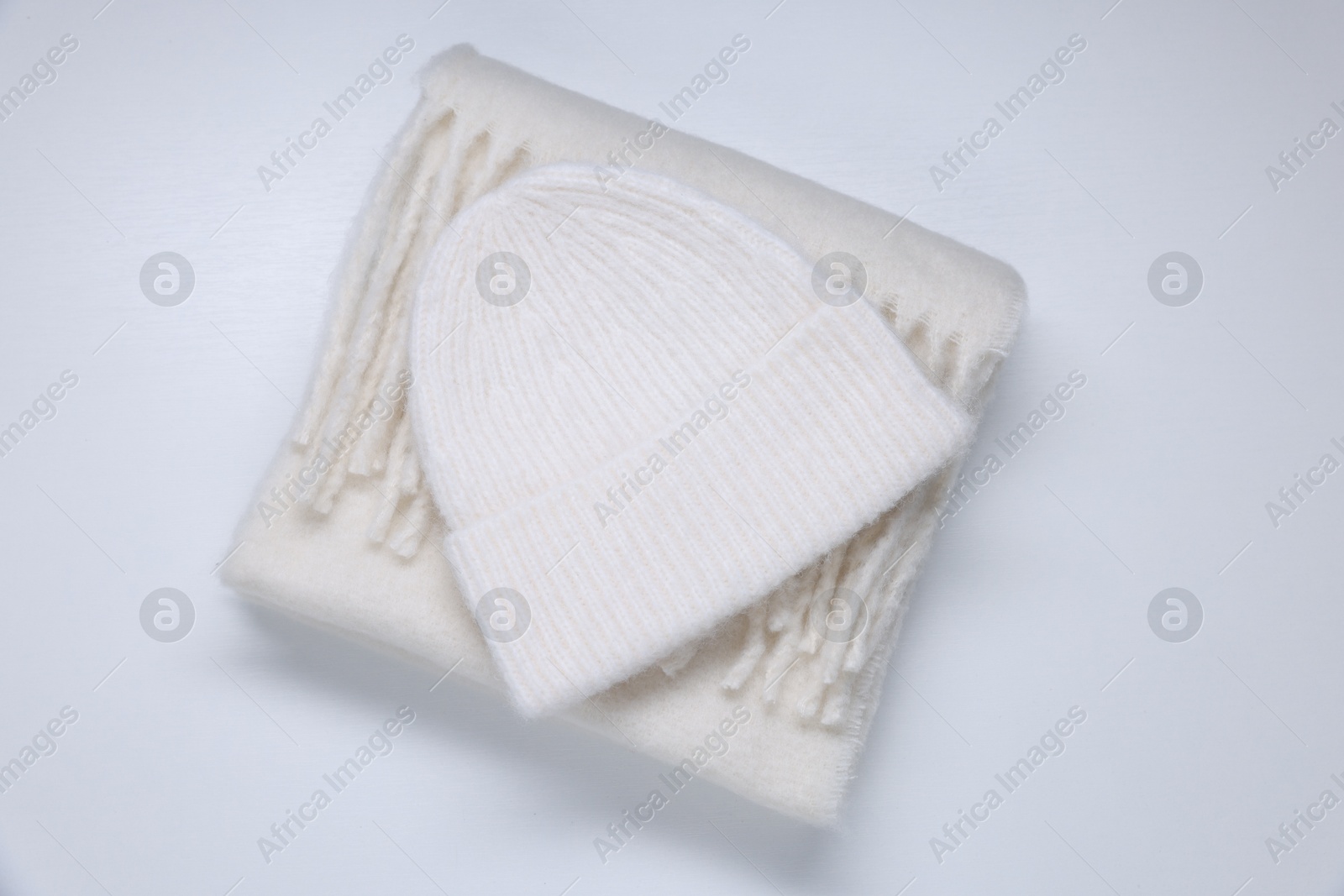 Photo of Stylish knitted hat and warm scarf on white wooden background, top view