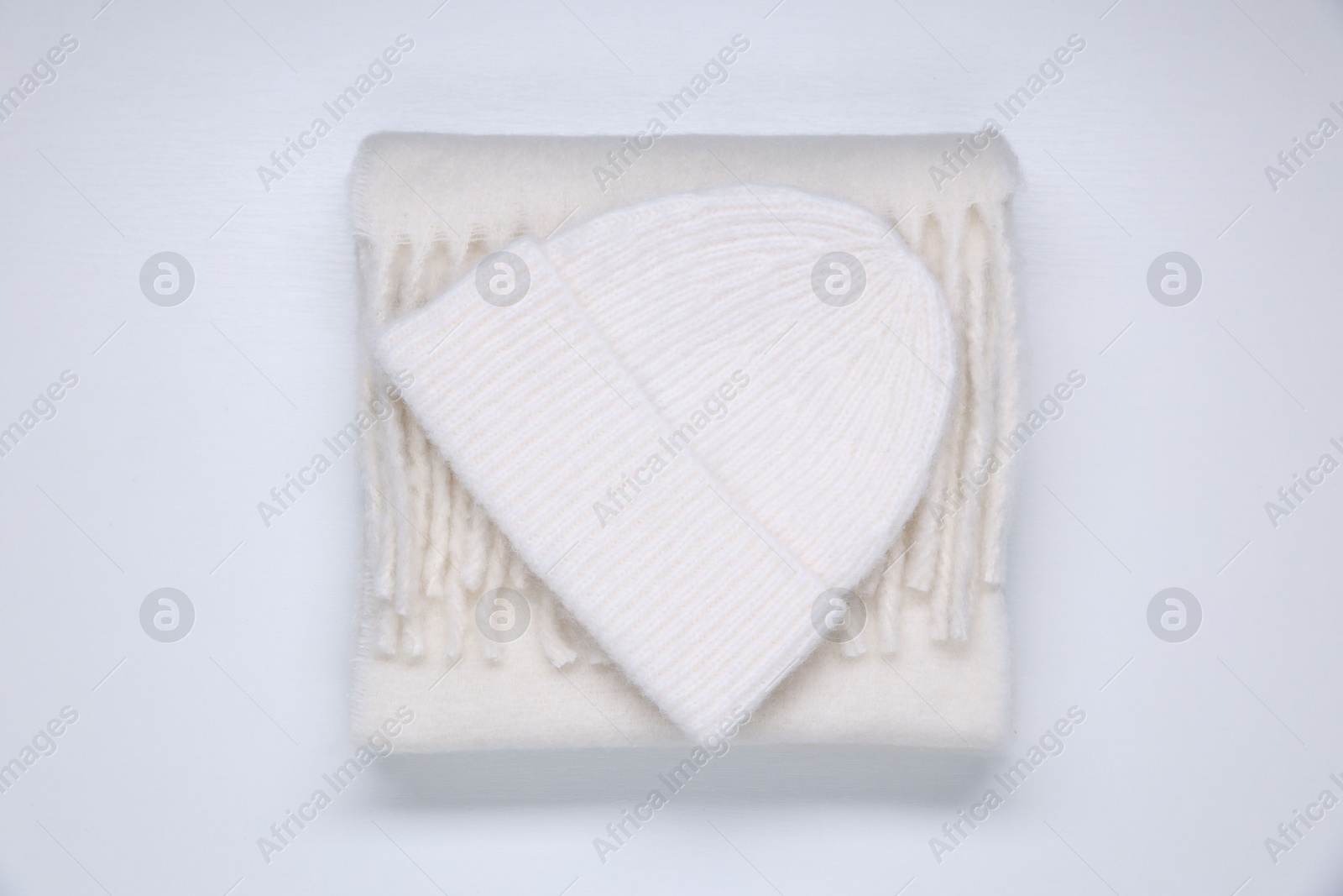 Photo of Stylish knitted hat and warm scarf on white wooden background, top view