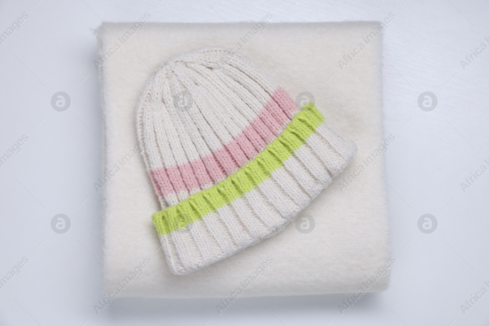 Photo of Stylish knitted hat and warm scarf on white wooden background, top view