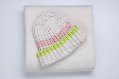 Photo of Stylish knitted hat and warm scarf on white wooden background, top view