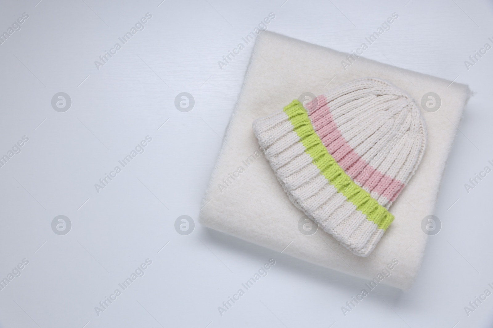 Photo of Stylish knitted hat and warm scarf on white background, top view. Space for text