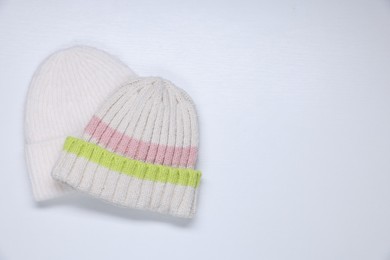 Photo of Stylish knitted hats on white background, top view. Space for text