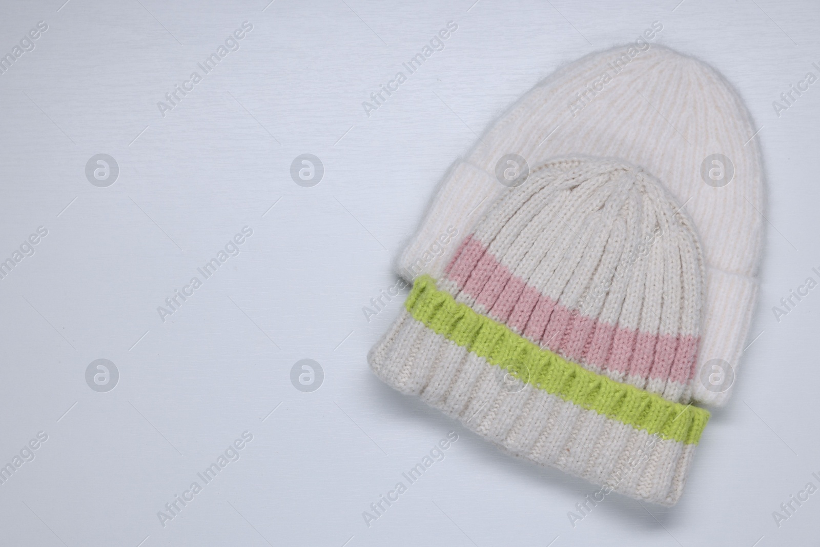 Photo of Stylish knitted hats on white background, top view. Space for text