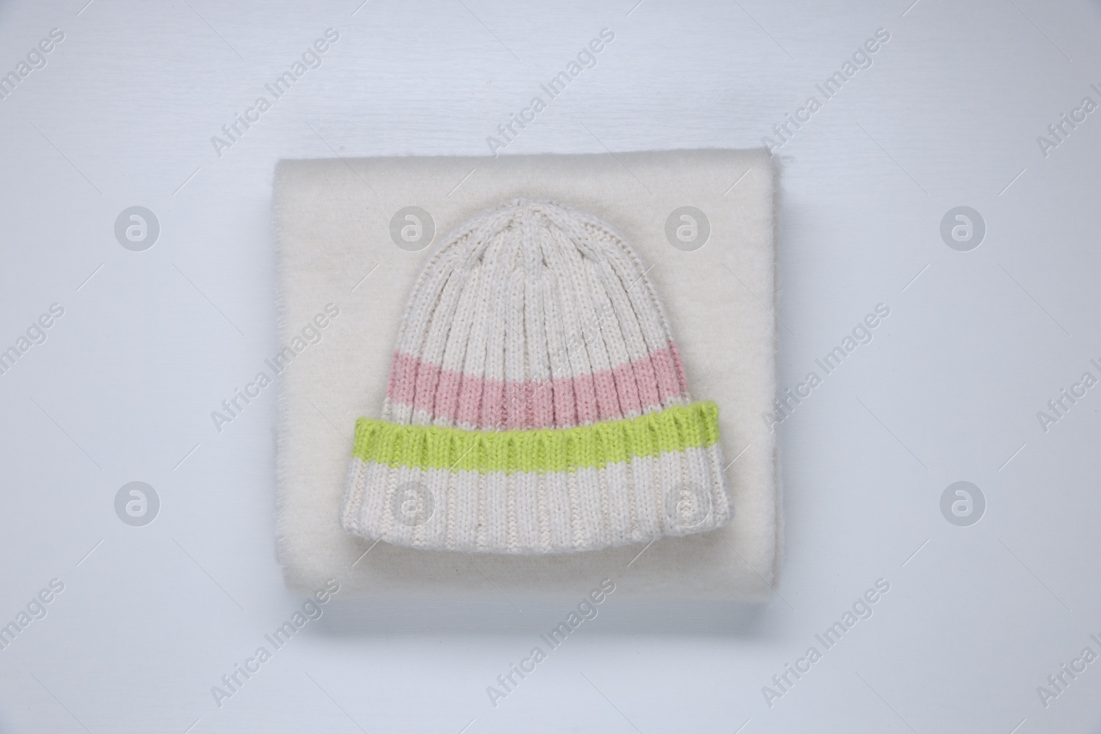 Photo of Stylish knitted hat and warm scarf on white background, top view