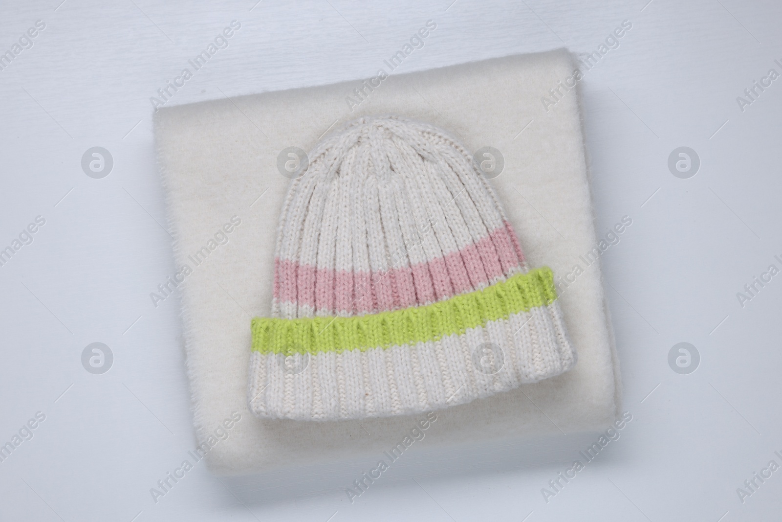 Photo of Stylish knitted hat and warm scarf on white background, top view