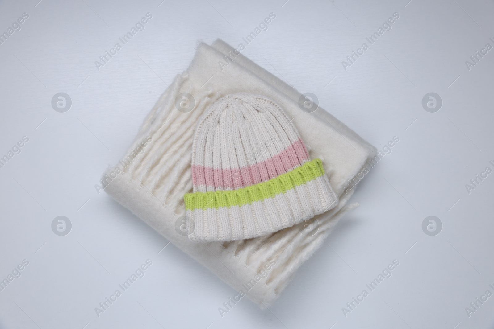 Photo of Stylish knitted hat and warm scarf on white background, top view