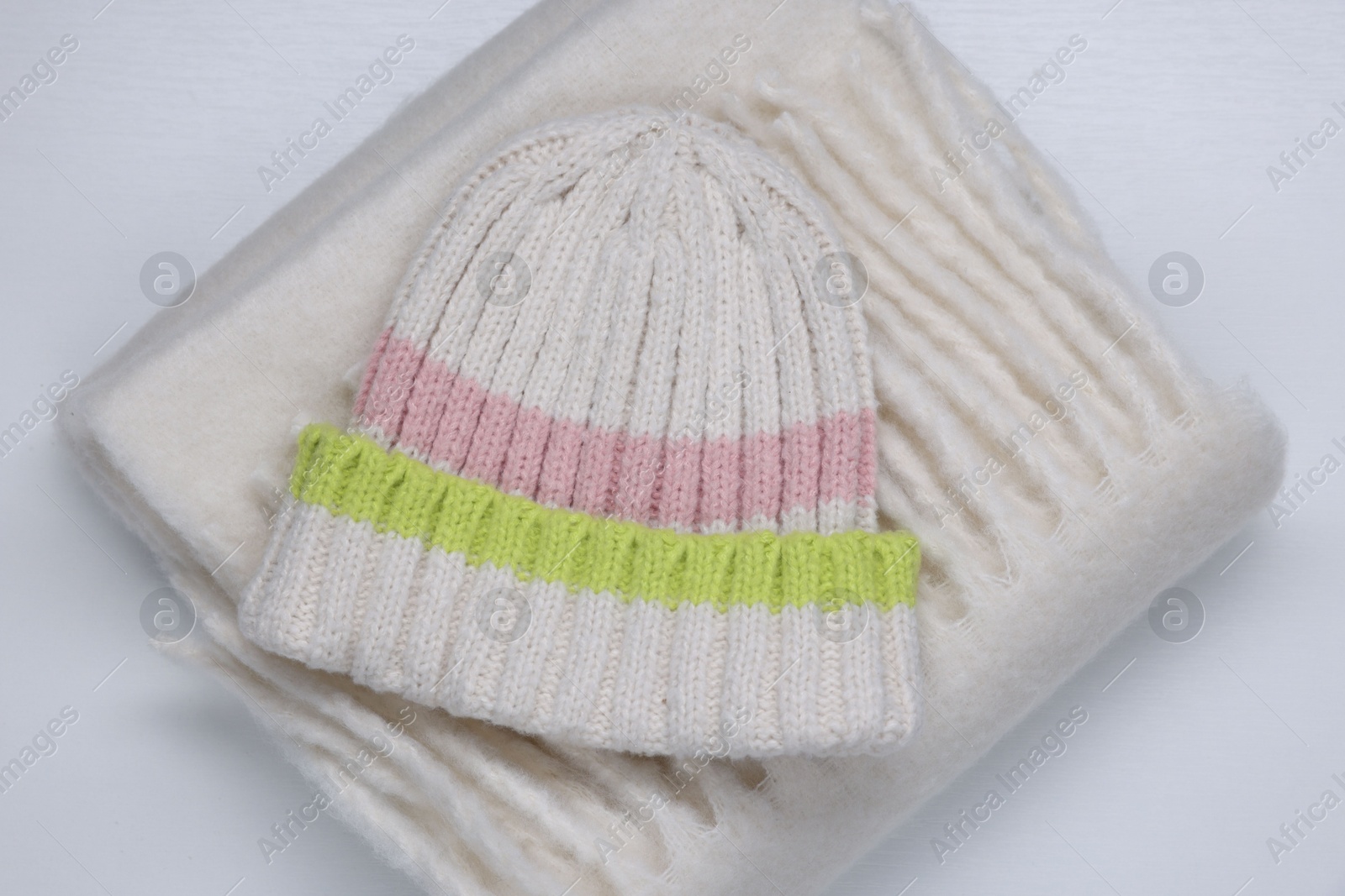 Photo of Stylish knitted hat and warm scarf on white background, top view