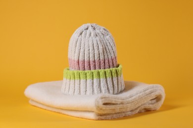 Photo of Stylish knitted hat and warm scarf on yellow background