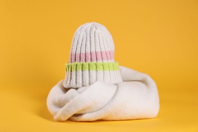 Photo of Stylish knitted hat and warm scarf on yellow background