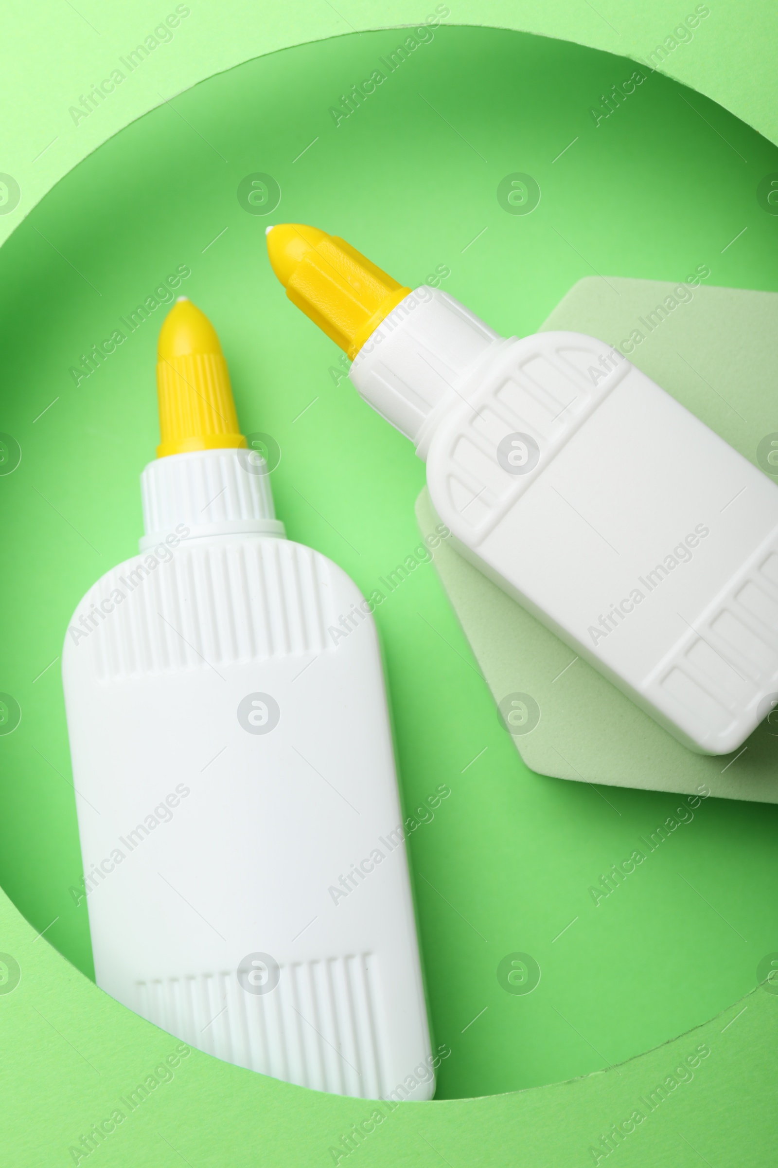 Photo of Bottles of glue on light green background, top view