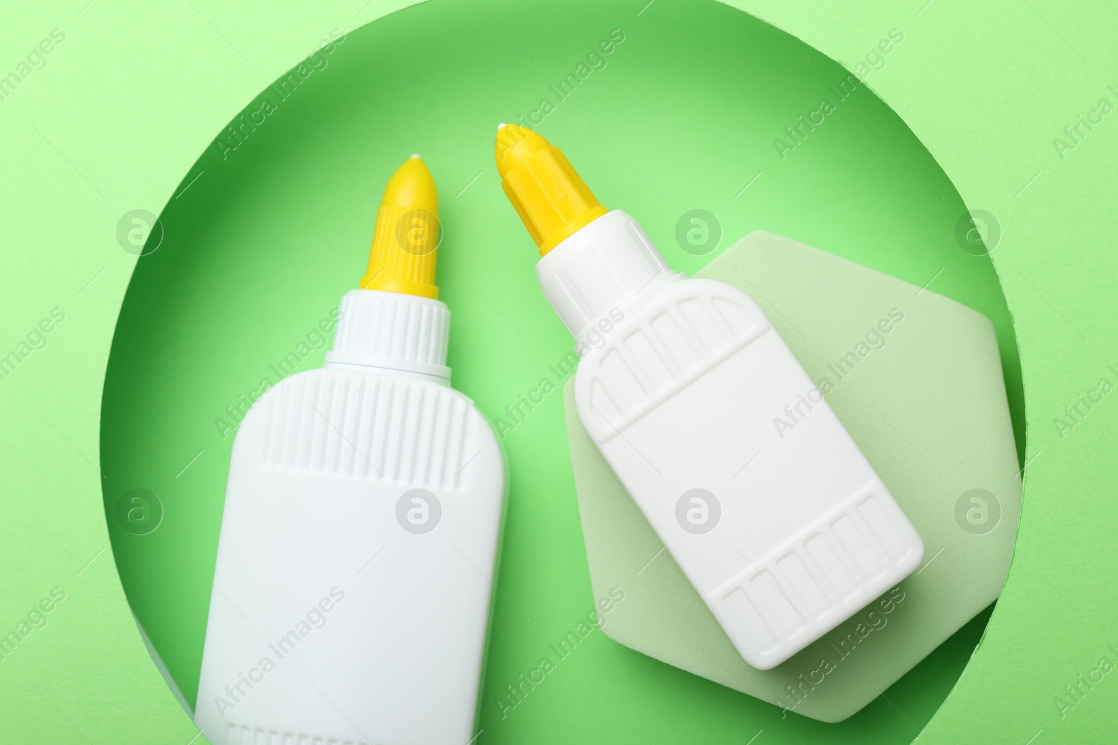 Photo of Bottles of glue on light green background, top view