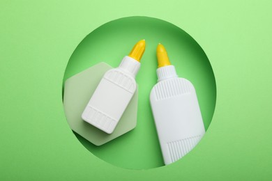 Photo of Bottles of glue on light green background, top view