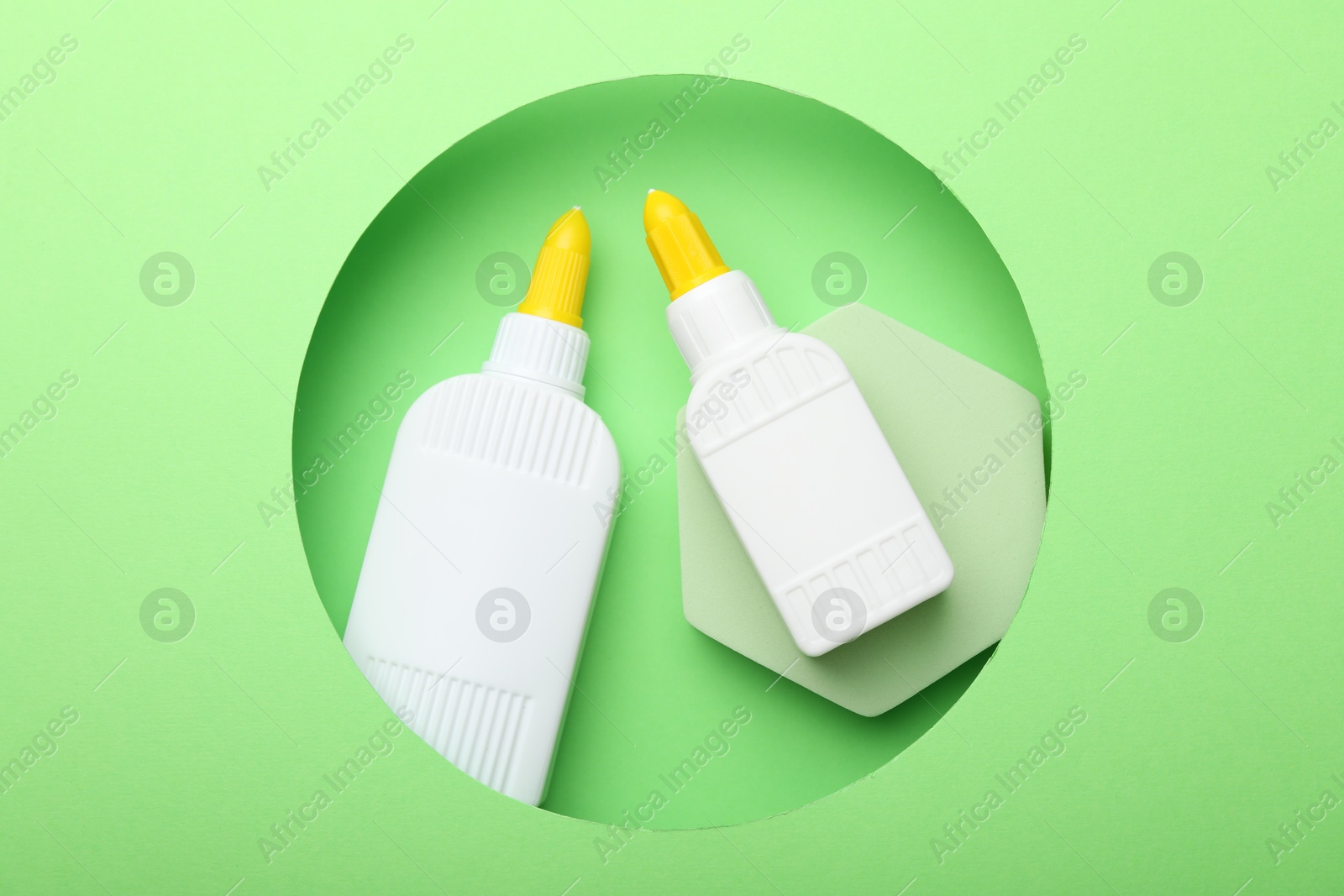 Photo of Bottles of glue on light green background, top view