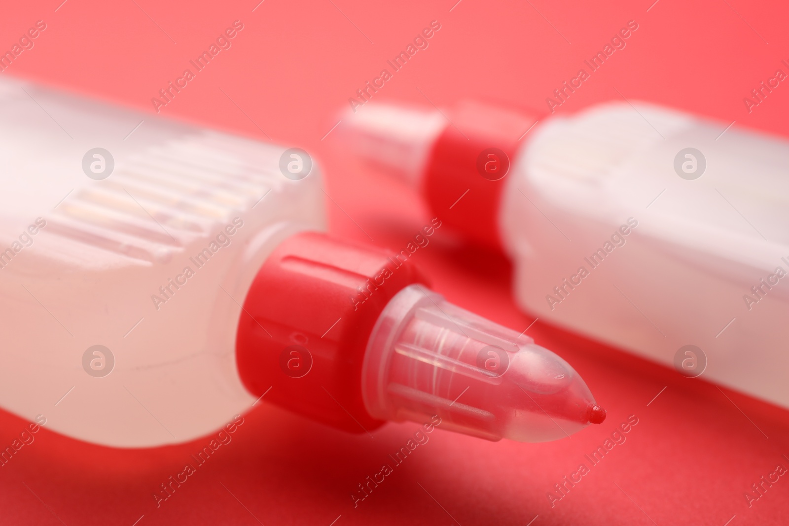 Photo of Bottles of glue on red background, closeup