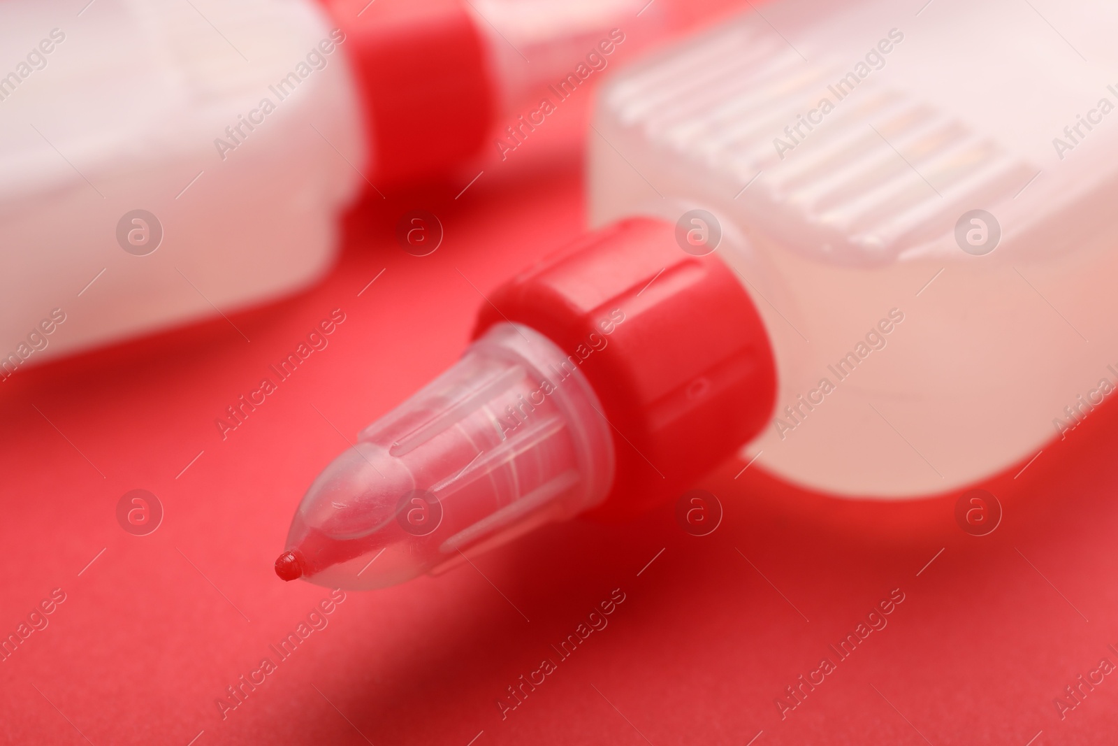 Photo of Bottles of glue on red background, closeup