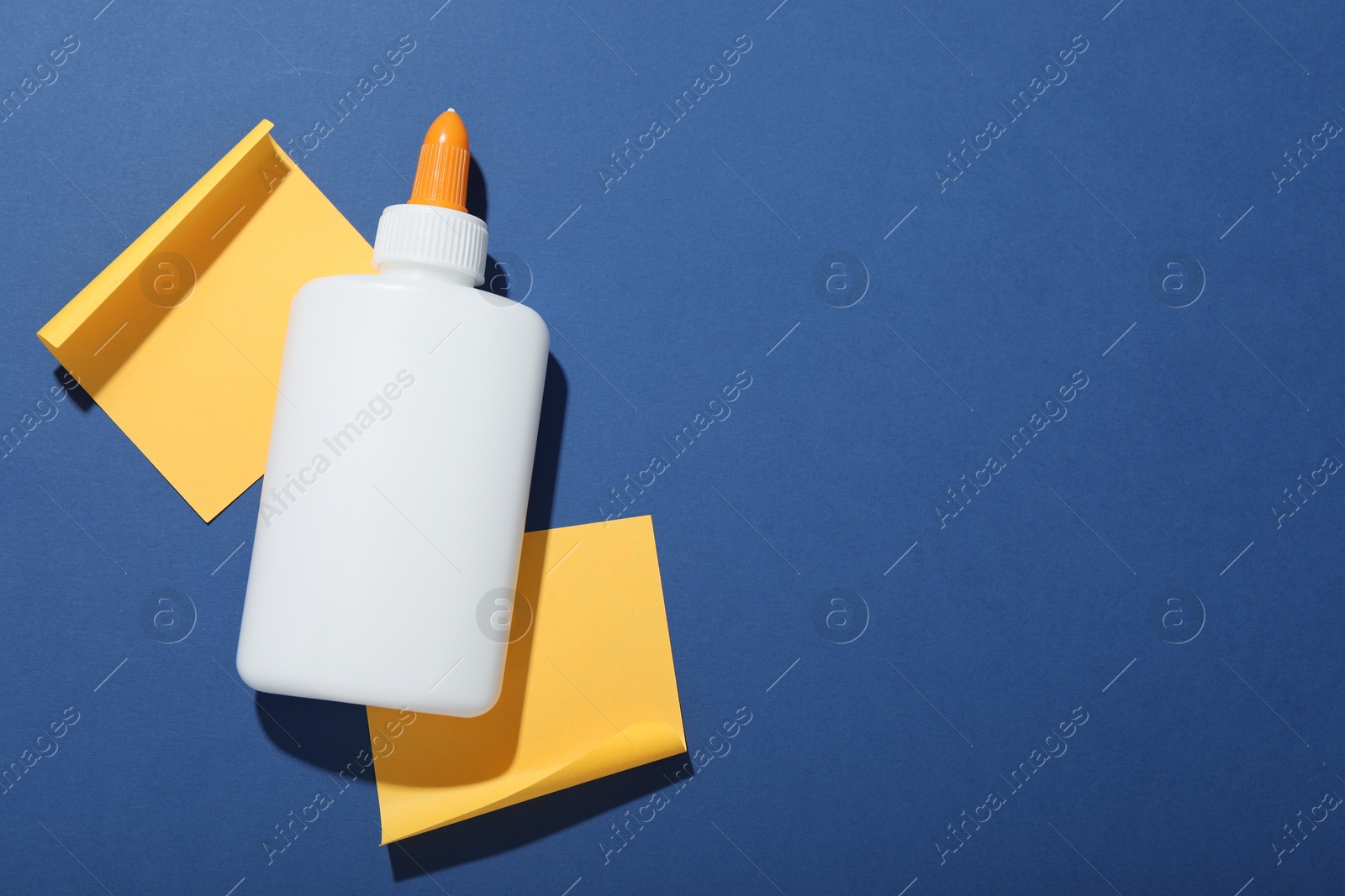 Photo of Bottle of glue and notes on blue background, flat lay. Space for text